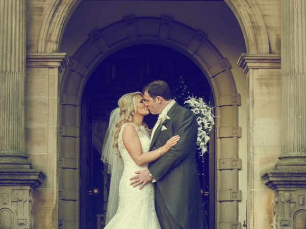 bride and groom kissing in archway, cheshire wedding photographer, crewe hall