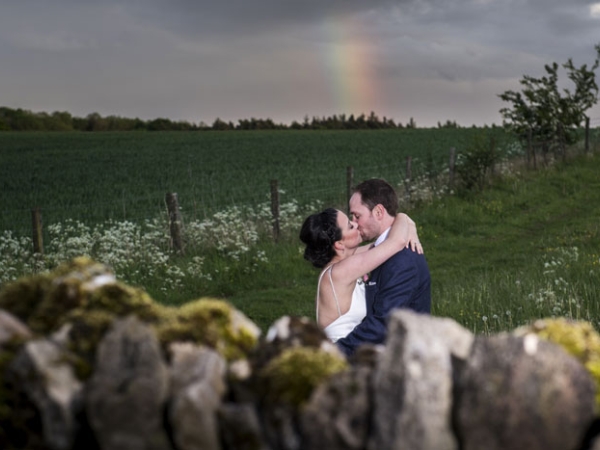 bride and groom kiss in a field, rainbow, gloucestershire wedding photographer, cripps barn