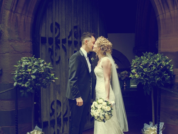 bride and groom kiss archway, cheshire wedding photographer, all saints church thelwall